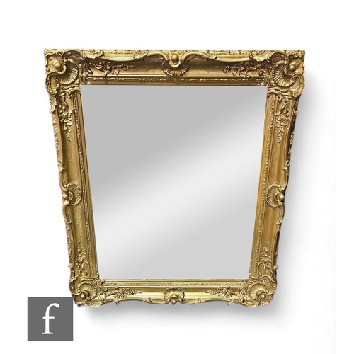 885 - A Louis XVI style gilt wall mirror, of rectangular from with lower carved apron, and upper scalloped... 