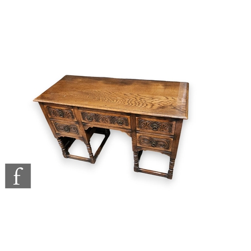 892 - A 17th Century style carved oak kneehole dressing table fitted with five drawers around an arched re... 