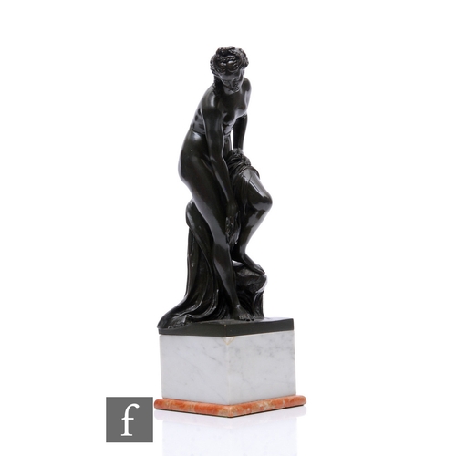 491 - A late 20th Century figure of Venus dressed in a classical robe and washing her legs, on a white mar... 