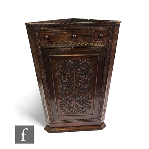 662 - A late 19th Century carved oak hanging corner cupboard enclosed by an oval panel and moulded edge do... 