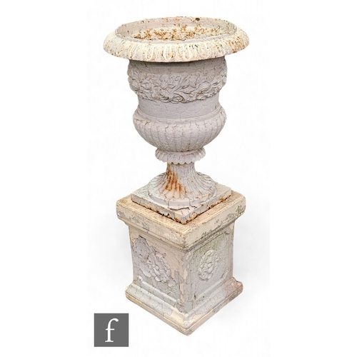 672 - A 19th Century Campana shaped cast iron terrace urn on a half fluted base below an border of flowers... 