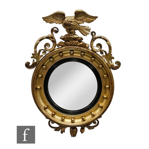 685 - A 20th Century Regency style circular gilt wall mirror, surmounted with a winged eagle flanked by sc... 