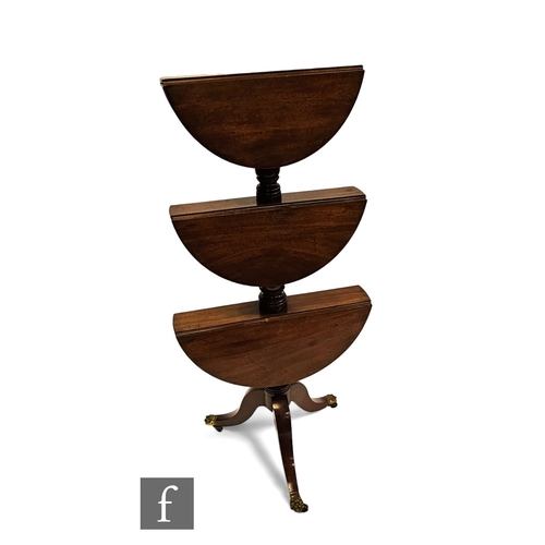 702 - A George III mahogany graduated three tier drop flap circular dumb waiter, on splayed legs terminati... 