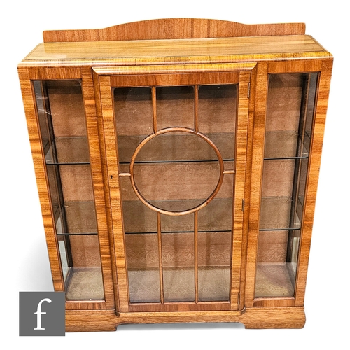 706 - A 1930s Art Deco walnut breakfront display cabinet enclosed by a circular bar glazed door below a sh... 