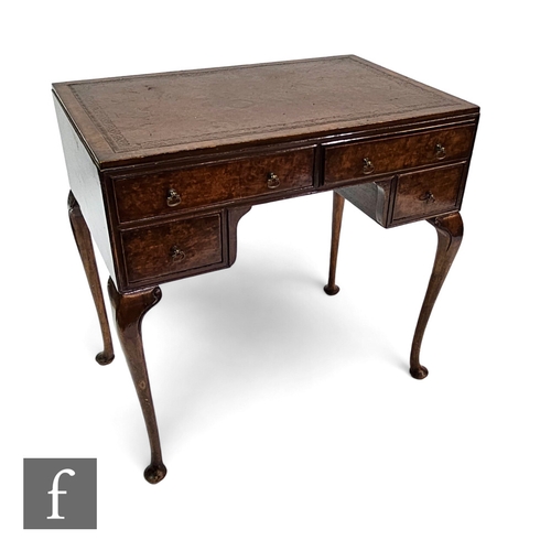 713 - A small early 1930s walnut kneehole desk fitted with four drawers below a leather top, brass drop ha... 