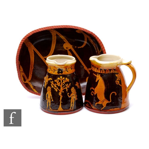 105 - A pair of contemporary studio pottery slip ware jugs of flared form with strap handles, one decorate... 