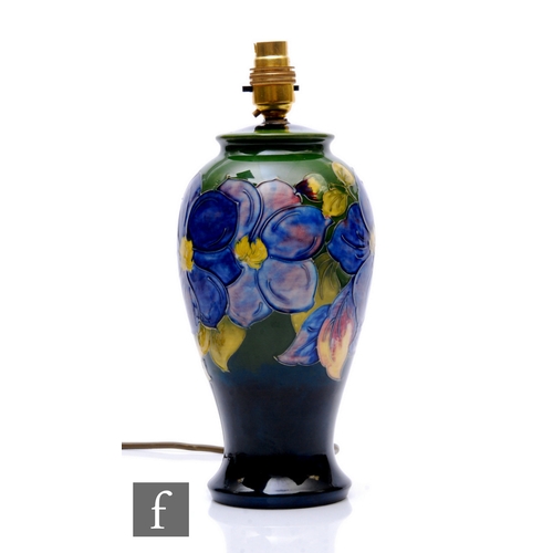 121 - A Moorcroft pottery lampbase of inverse baluster form, tubelined clematis pattern over graduated gre... 