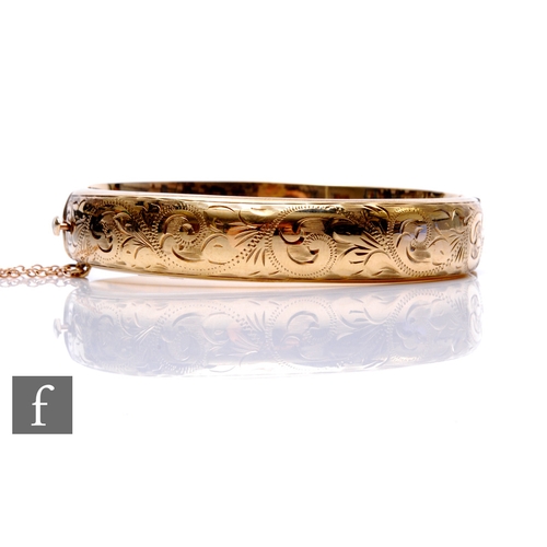 132 - A 9ct hallmarked hinged bangle with part engraved foliate decoration, weight 19g, Birmingham 1956.