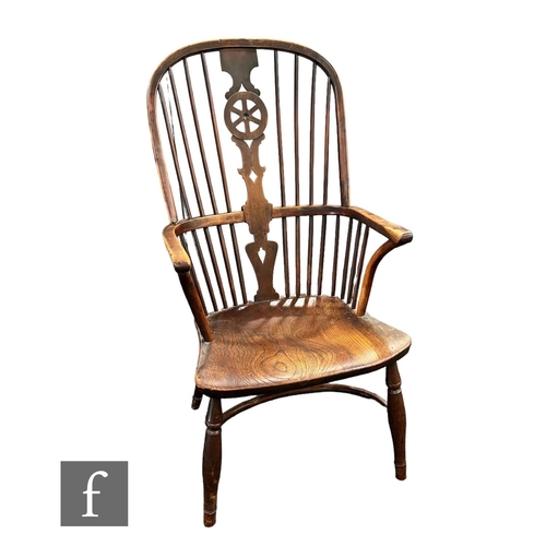 748 - A 19th Century yewwood and elm seat Windsor elbow chair, wheel back splat, on splayed legs united by... 