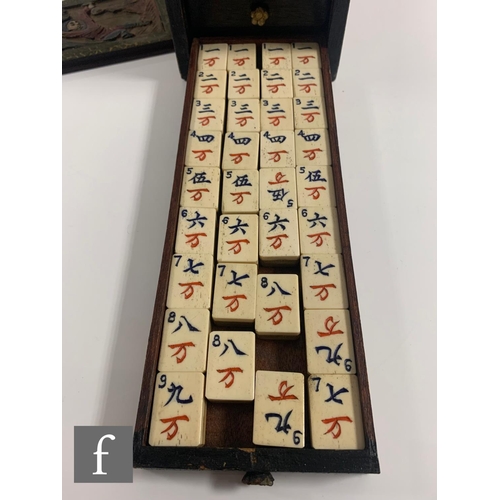 551 - A 1920s/30s bone mahjong set, the carved coloured case with sliding front door containing five drawe... 