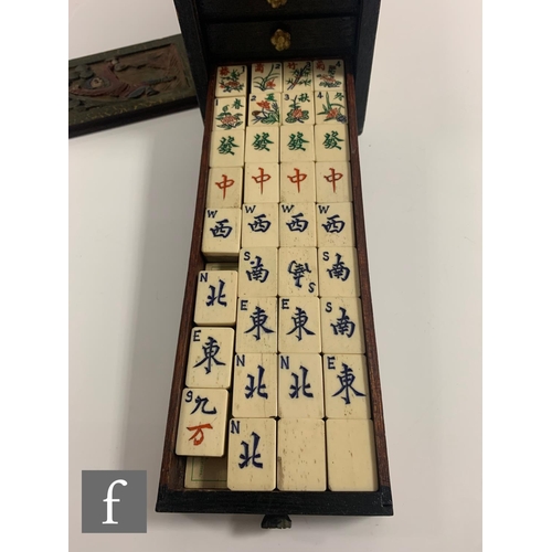 551 - A 1920s/30s bone mahjong set, the carved coloured case with sliding front door containing five drawe... 