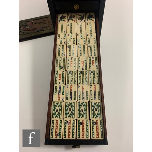 551 - A 1920s/30s bone mahjong set, the carved coloured case with sliding front door containing five drawe... 