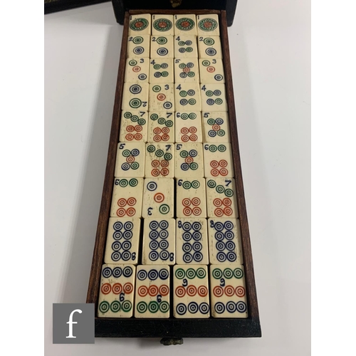 551 - A 1920s/30s bone mahjong set, the carved coloured case with sliding front door containing five drawe... 