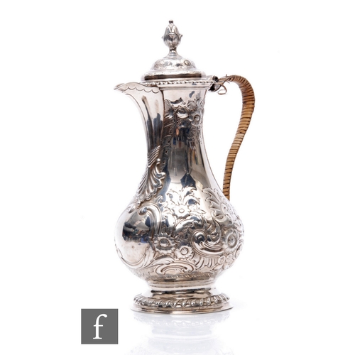 22 - A hallmarked silver coffee pot of baluster form with later engraved and embossed foliate decoration,... 