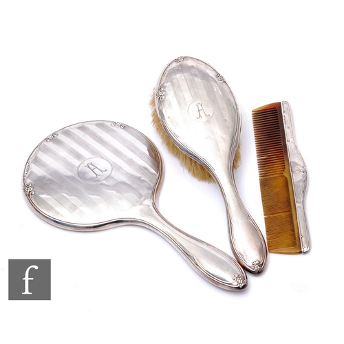 32 - A hallmarked silver three piece brush set, hand mirror, brush and comb, Chester 1927, some damage. (... 