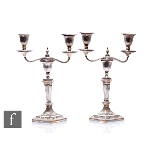 38 - A pair of hallmarked silver two light candelabra, square bases below reeded column, capital and scro... 