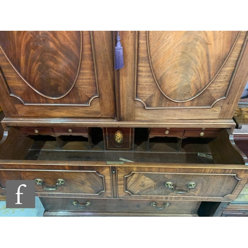 635 - A George III mahogany secretaire linen press, the converted hanging space enclosed by a pair of oval... 