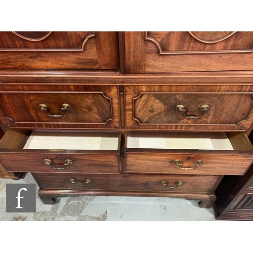 635 - A George III mahogany secretaire linen press, the converted hanging space enclosed by a pair of oval... 