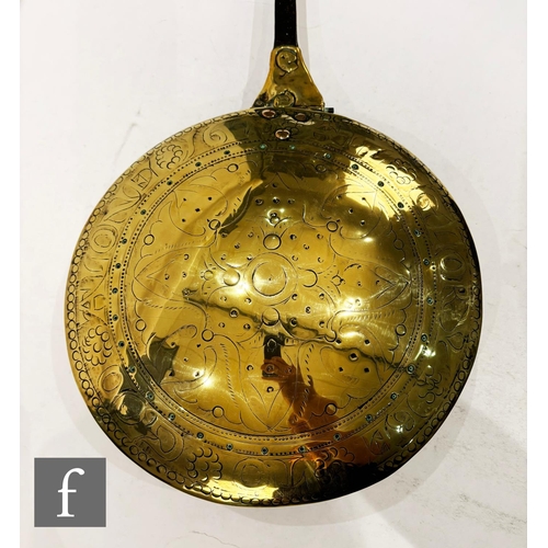 479 - A 17th Century brass warming pan, the domed centre engraved with scroll and leaf design and the oute... 