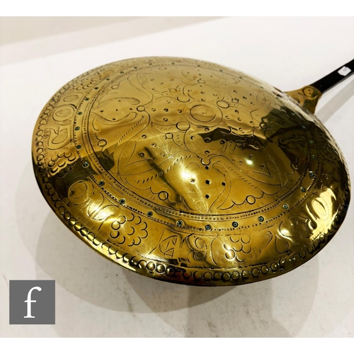 479 - A 17th Century brass warming pan, the domed centre engraved with scroll and leaf design and the oute... 