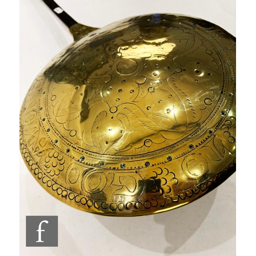 479 - A 17th Century brass warming pan, the domed centre engraved with scroll and leaf design and the oute... 