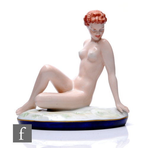 84 - A Royal Dux Art Deco figure, modelled as a young woman seated on oval naturalistic moulded base with... 