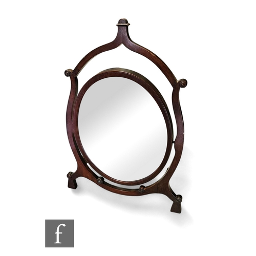 653 - An Edwardian mahogany dressing table mirror, the oval bevelled edge plate suspended on a shaped fram... 