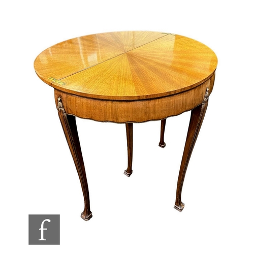 591 - A 20th Century French demi lune fold over table, the radiating walnut top with parcel gilt detail on... 