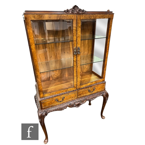 598 - A Queen Anne style carved figured walnut two door display cabinet, the glass shelf interior enclosed... 