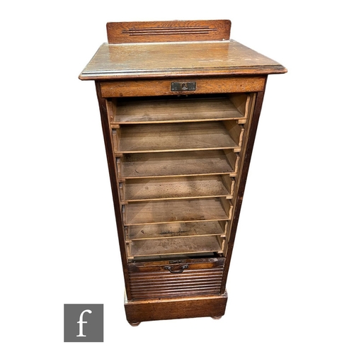 600 - A 1930s oak filing cabinet enclosed by a tambour shutter door, height 121cm x depth 45cm x width 48c... 