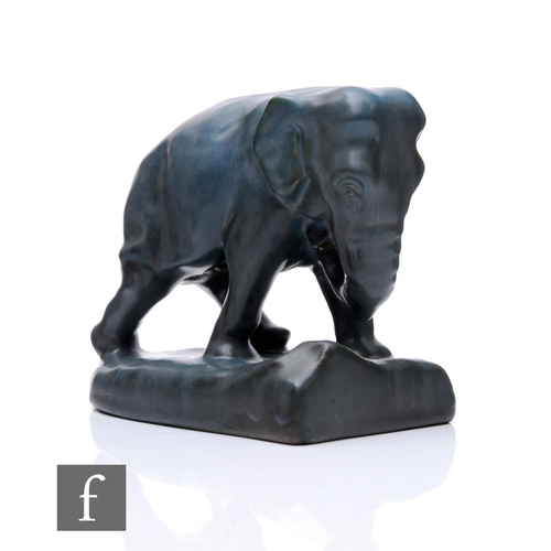 572 - Rookwood Art Pottery - An elephant bookend, dark grey glaze, modelled striding, on naturalistic base... 