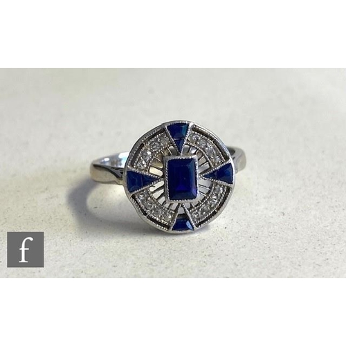 264 - An Art Deco 18ct white gold sapphire and diamond ring, circular head set with central emerald cut sa... 