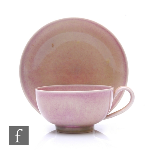 114 - Ruskin Pottery - A tea cup and saucer of circular wide bowled form, dusty pink mottled and flecked g... 