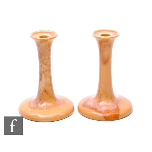 122 - Ruskin Pottery - A pair of candlesticks, with wide spreading circular foot and tall swept column and... 