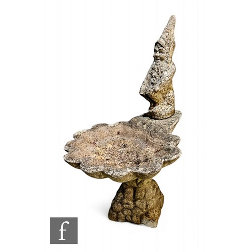 571 - A 20th Century composite stone scallop shaped bird bath on a pedestal with gnome attachment, height ... 