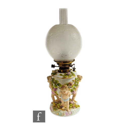 149 - A Sitzendorf porcelain lamp base, circa 1880, modelled as three standing putti supporting floral enc... 