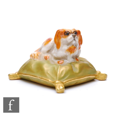 152 - A Royal Worcester figure of a King Charles spaniel, seated on a shot silk tasselled cushion, circa 1... 