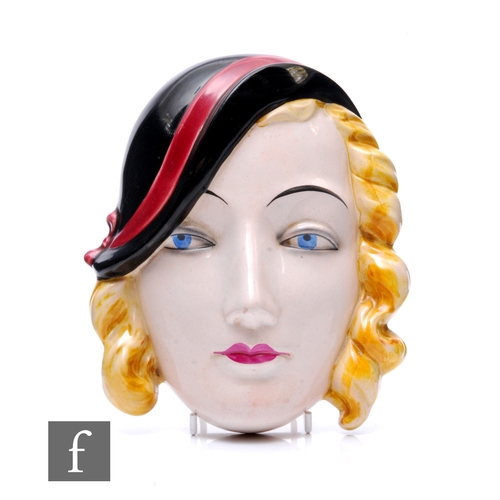 589 - Goebel - An Art Deco ceramic wall mask, modelled as a lady with blonde curls and wearing black hat w... 