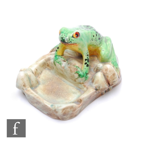 660 - E. Radford - A 1930s novelty ashtray modelled as a seated frog on a rock with hand enamelled decorat... 