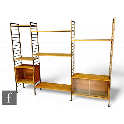 934 - Staples - A mid Century teak bronzed metal Ladderax modular shelving system, with three banks of she... 