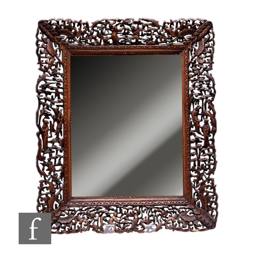 489 - A 20th Century Chinese carved hardwood framed mirror, the pierced frame decorated with manchu figure... 