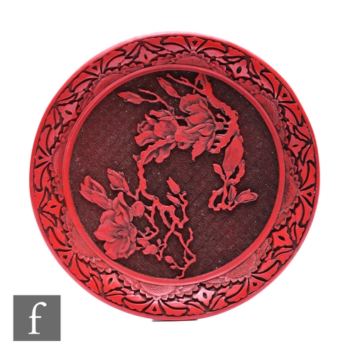 499 - A Chinese 20th Century cinnabar lacquer dish, carved with orchids before a scroll ground, diameter 2... 