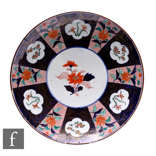 511 - A Japanese late Meiji period (1868-1912) imari charger, decorated with segmented floral panels, in r... 