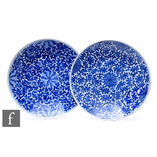 516 - A pair of Kangxi style blue and white chargers, decorated with central lotus designs with meandering... 