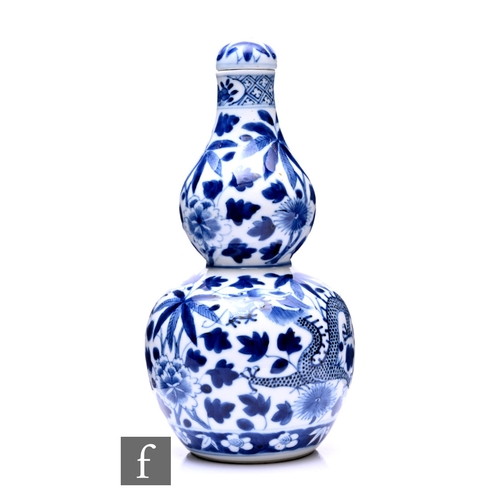 525 - A Chinese Kangxi style double-gourd form vase, the blue and white vase surmounted by a domed cover, ... 