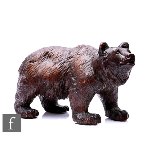 31 - A late 19th Century Black Forest carved walnut model of an adult bear, inset glass eyes, length 34cm... 