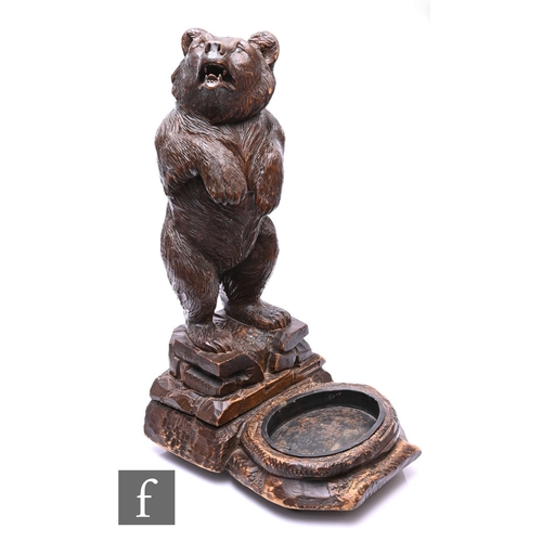 32 - A late 19th Century carved walnut Black Forest bear umbrella stand, standing in begging pose on a ro... 