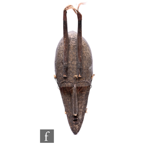 572 - An African Bambara Marka tribal carved and horned mask from Mali, with beaten metal decoration and t... 