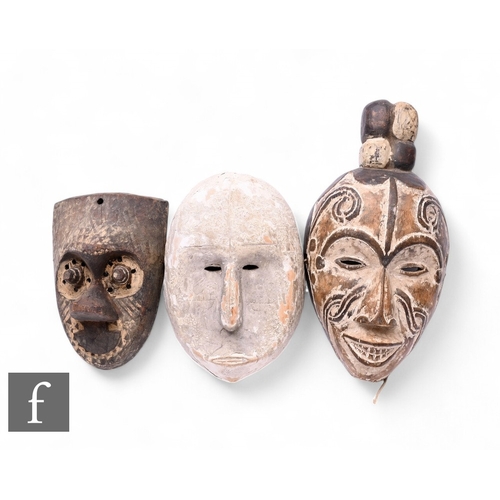 574 - Three African carved wood masks, to include a Fang mask from Gabon, with carved features and white p... 