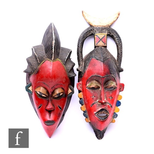 575 - An African Guro mask from Ivory Coast, hand carved in wood and painted in red, with details picked o... 